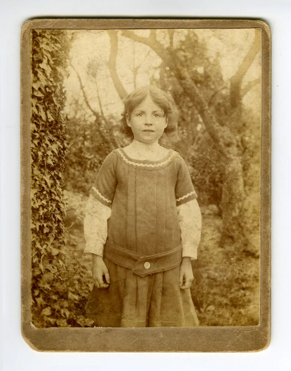 An antique sepia portrait of a girl, creased and yellowed with age
