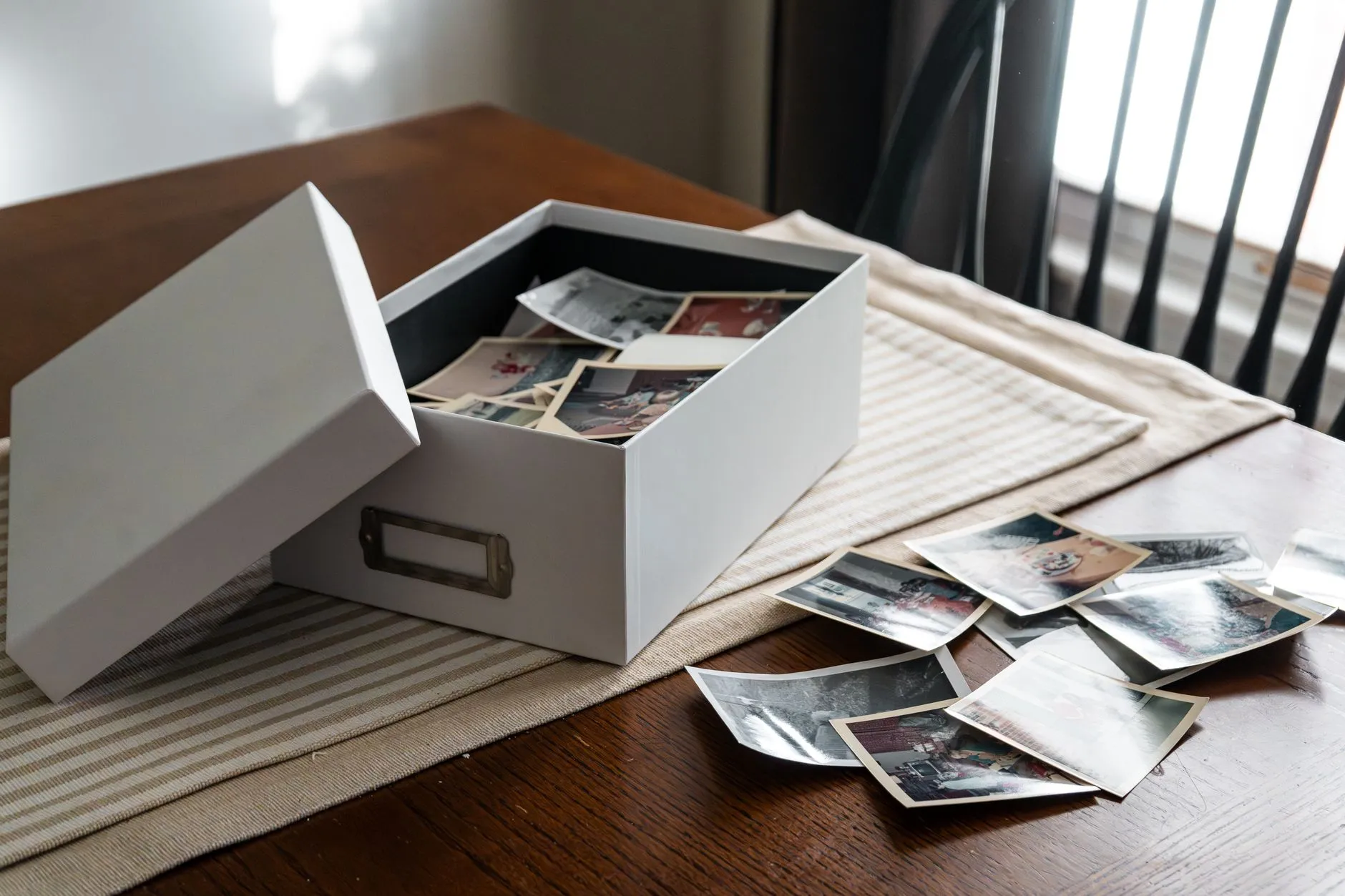 An open box of vintage family photographs on a wooden table